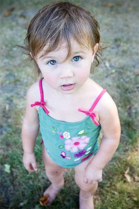A child looking up at the camera outdoors