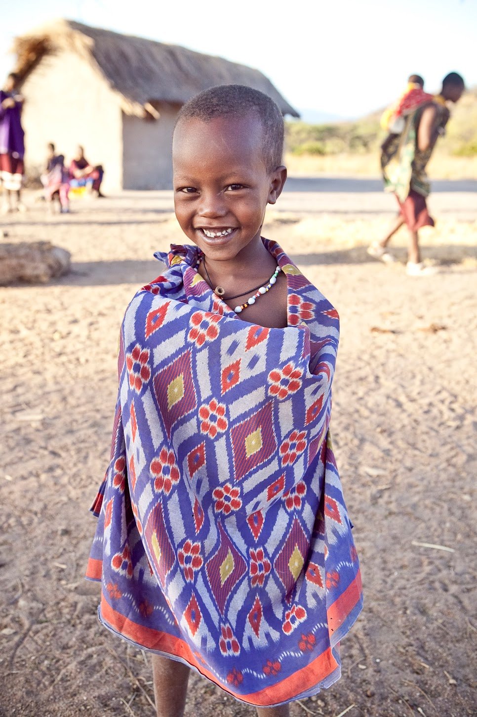 A smiling child wearing a colorful patterned wrap