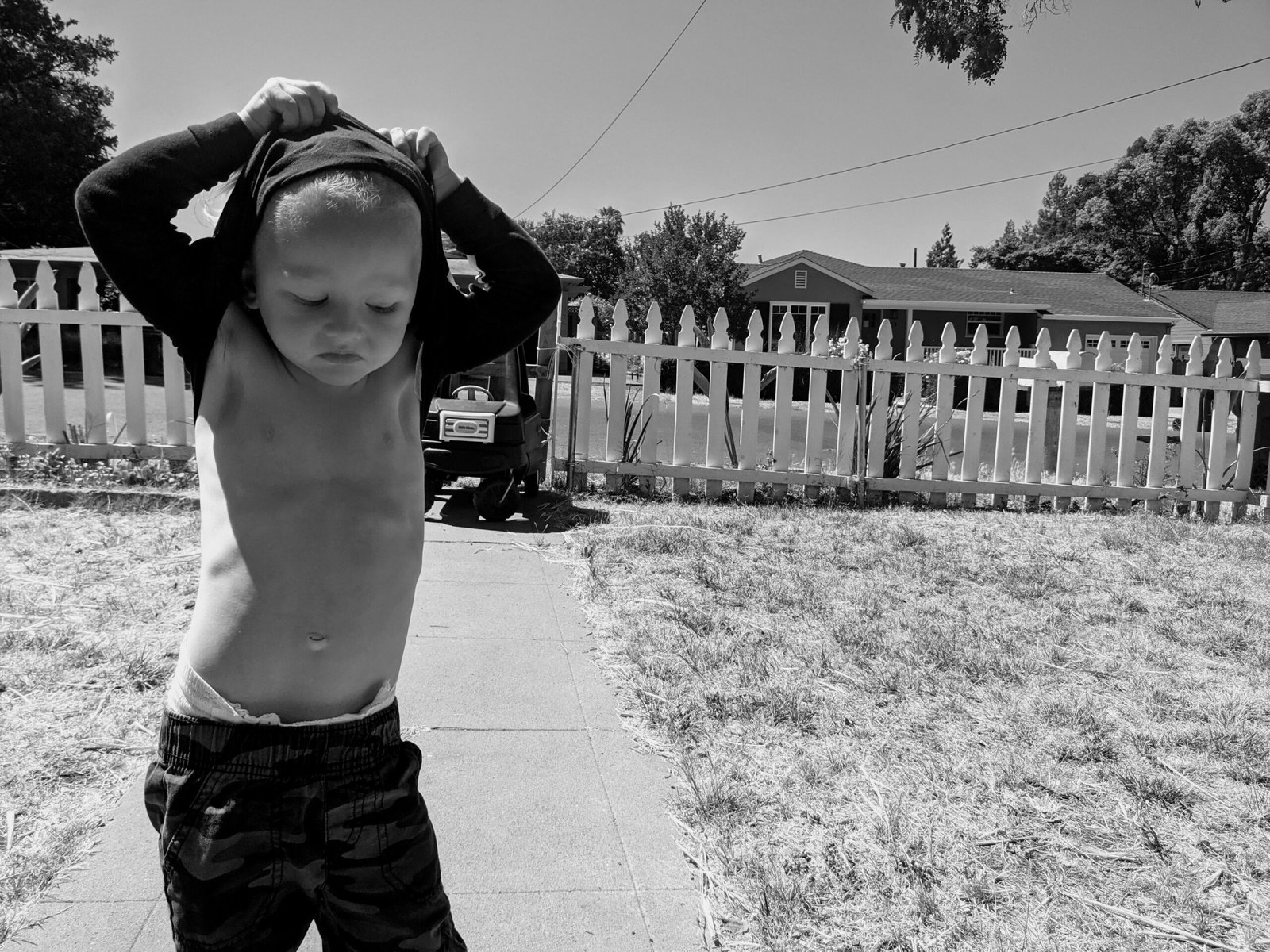 A child pulling a shirt over their head outdoors